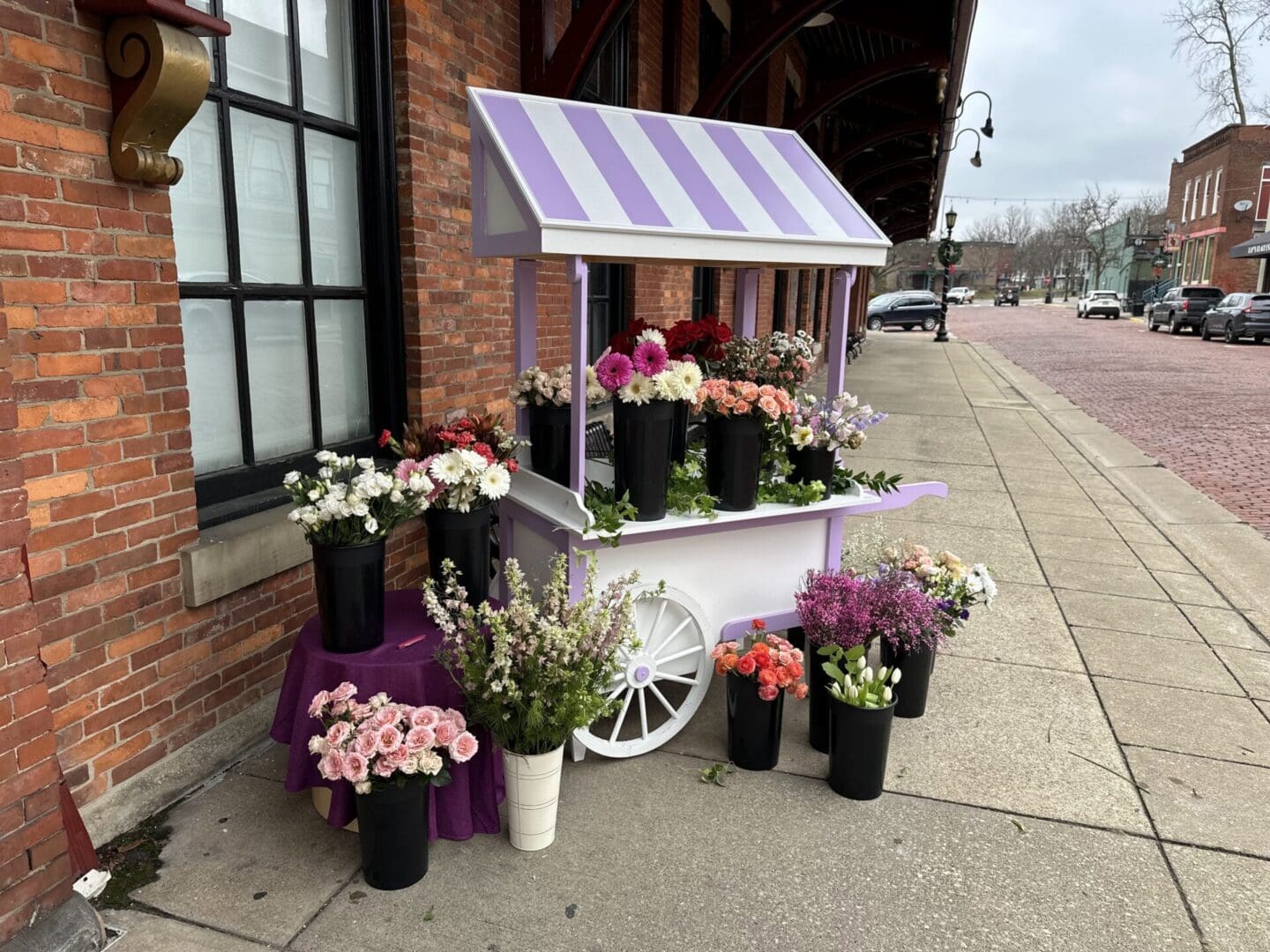 A flower cart with flowers on the side of the street.