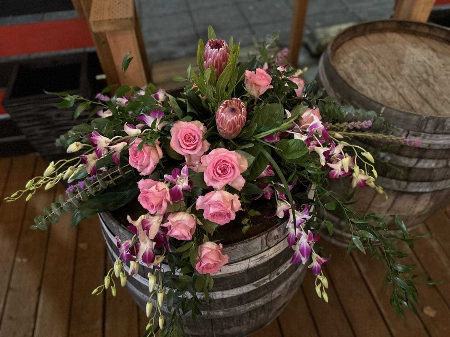 A bouquet of flowers in a barrel on the ground.